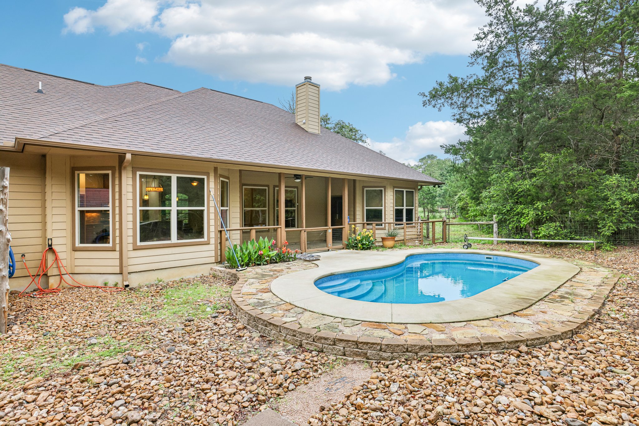 267 Corral Road Smithville, TX 78957 - Photo 35 of 40 In-ground swimming pool with stone surround and coping, complemented by a covered patio with wood railings