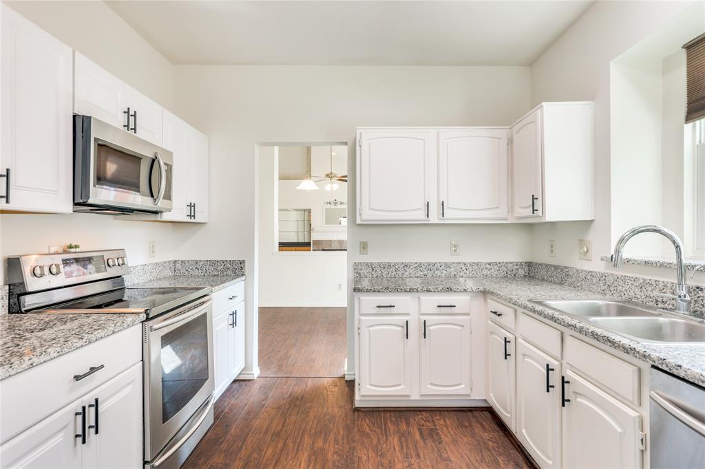 2151 Falcon Ridge Drive Carrollton, TX 75010 - Photo 18 of 40 a kitchen with stainless steel appliances granite countertop a stove top oven a sink dishwasher and a refrigerator with wooden floor