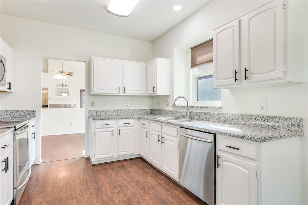 2151 Falcon Ridge Drive Carrollton, TX 75010 - Photo 19 of 40 a kitchen with granite countertop white cabinets and white appliances