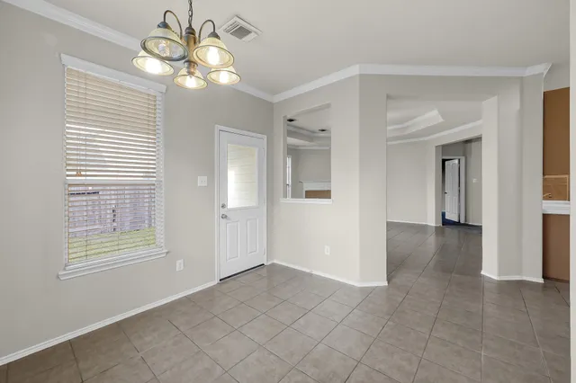 an empty room with windows and chandelier fan