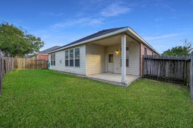 a view of a house with backyard and wooden fence