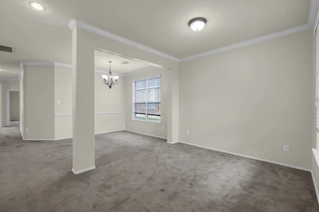 an empty room with chandelier fan and windows