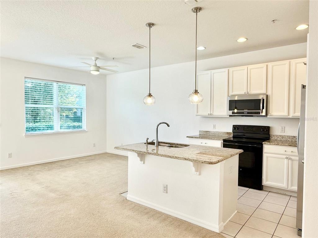 619 Fortanini Circle Ocoee, FL 34761 - Photo 6 of 36 a kitchen with stainless steel appliances granite countertop a sink a stove a microwave and a refrigerator