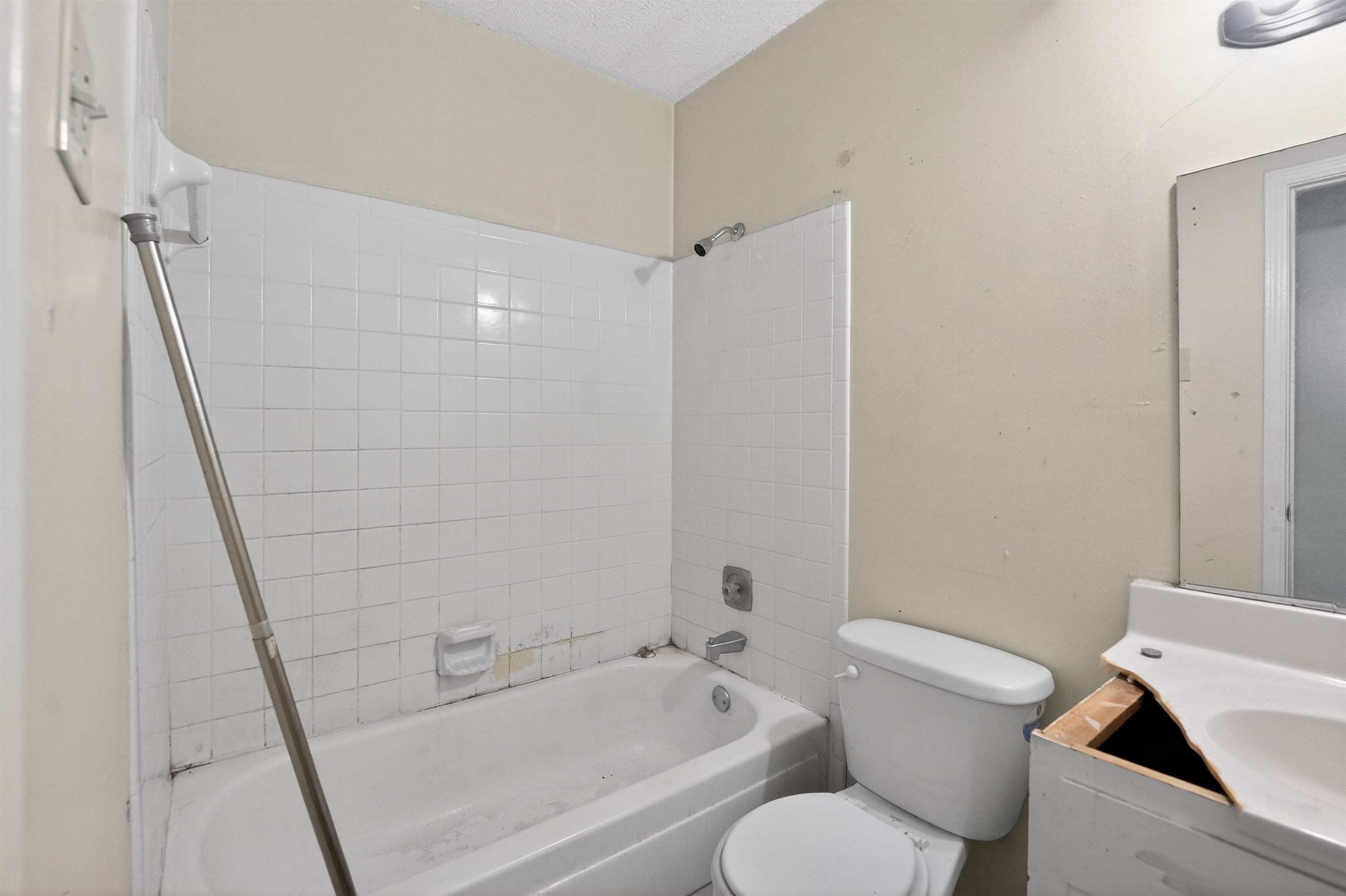 3372 Spring Shadow Drive Memphis, TN 38118 - Photo 27 of 35 Bathroom featuring a white bathtub with subway tile surround, a white toilet, and a vanity with an integrated sink