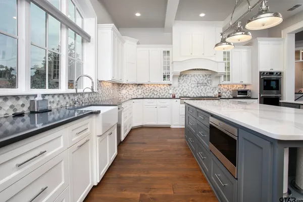 a large kitchen with granite countertop a sink and dishwasher a stove top oven with wooden floor
