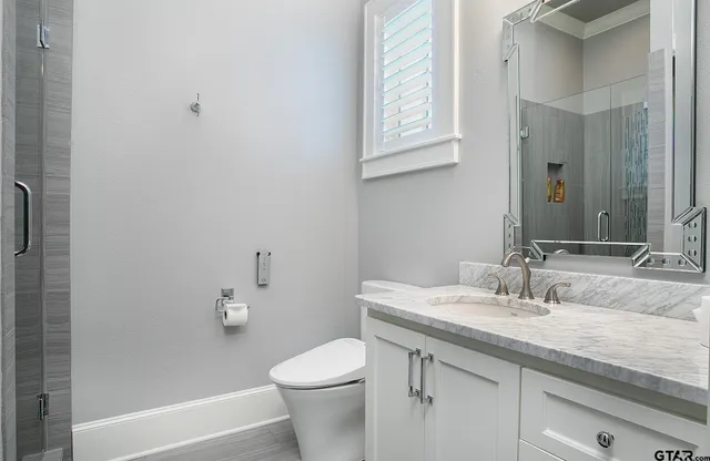 a bathroom with a granite countertop sink a toilet and a mirror