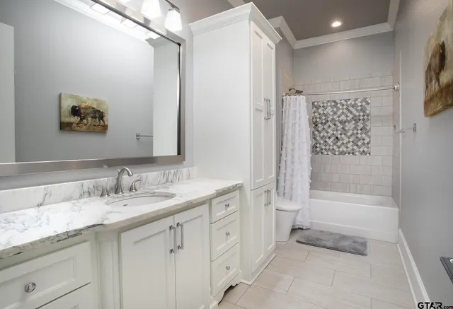 a spacious bathroom with a granite countertop sink a toilet a shower and a mirror