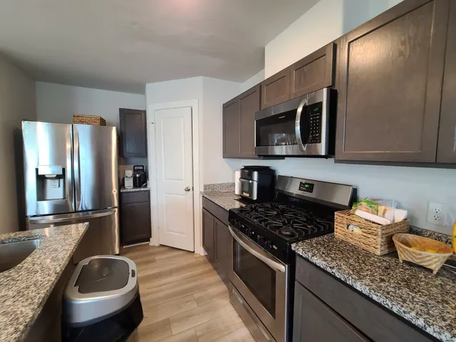 a kitchen with granite countertop stainless steel appliances a sink stove and refrigerator
