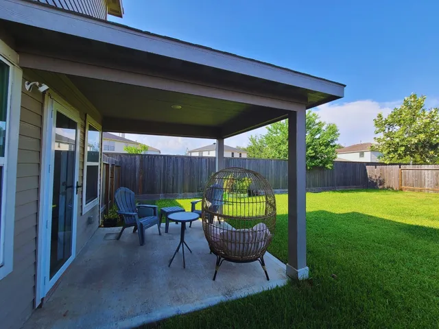 a view of a backyard with table and chairs potted plants with wooden fence