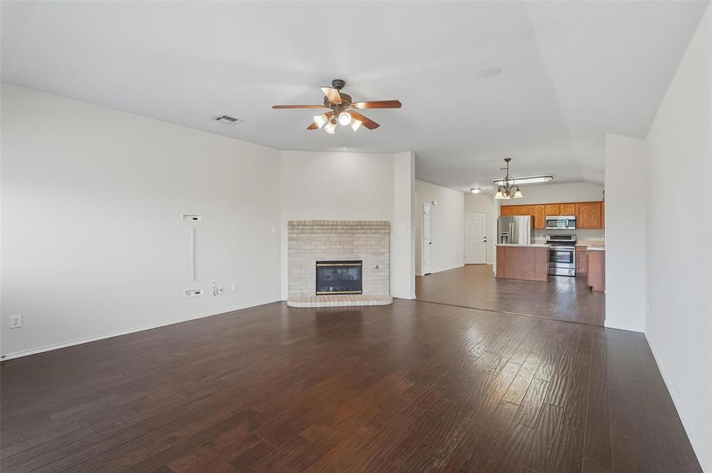 9822 Revolution Way Frisco, TX 75033 - Photo 5 of 29 an empty room with wooden floor fireplace and ceiling fan