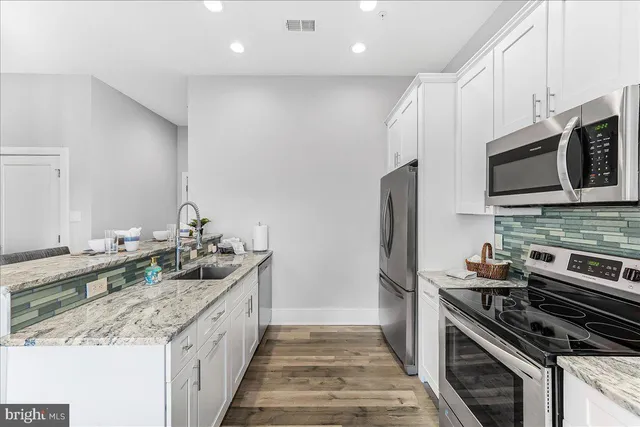 a kitchen with stainless steel appliances granite countertop a stove a sink and a microwave