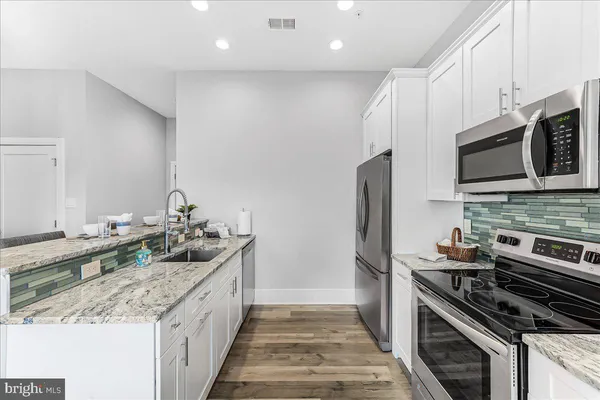 a kitchen with stainless steel appliances granite countertop a stove a sink and a microwave