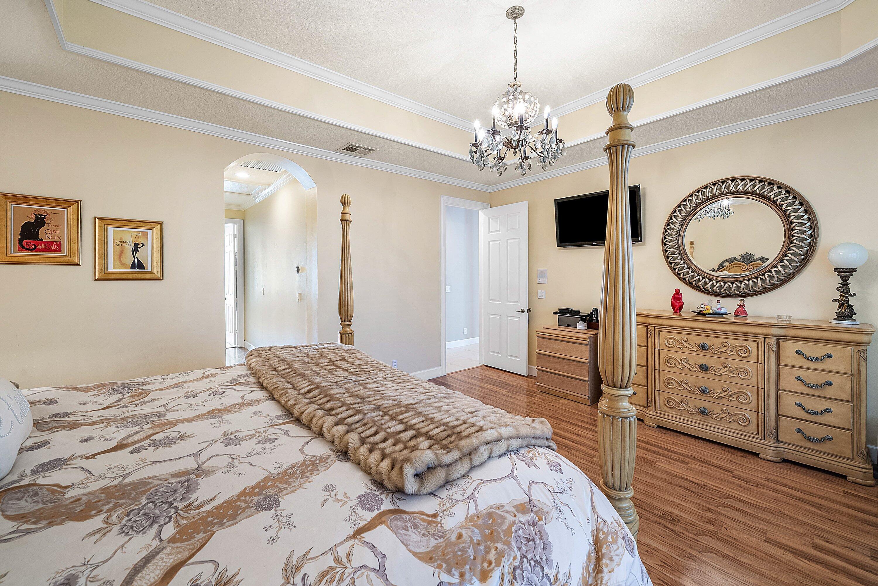 21374 Falls Ridge Way Boca Raton, FL 33428 - Photo 21 of 69 a bedroom with a bed a chandelier and a dresser