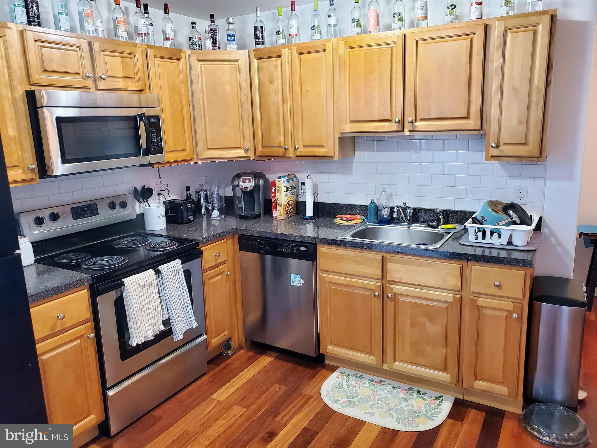 1525 North 17th Street, Unit 3 Philadelphia, PA 19121 - Photo 3 of 10 a kitchen with stainless steel appliances granite countertop a stove a sink dishwasher and microwave with wooden floor