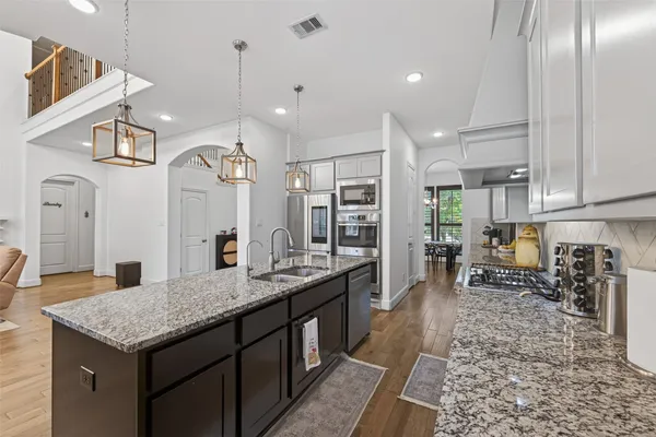 a kitchen with granite countertop a sink a counter space appliances and cabinets