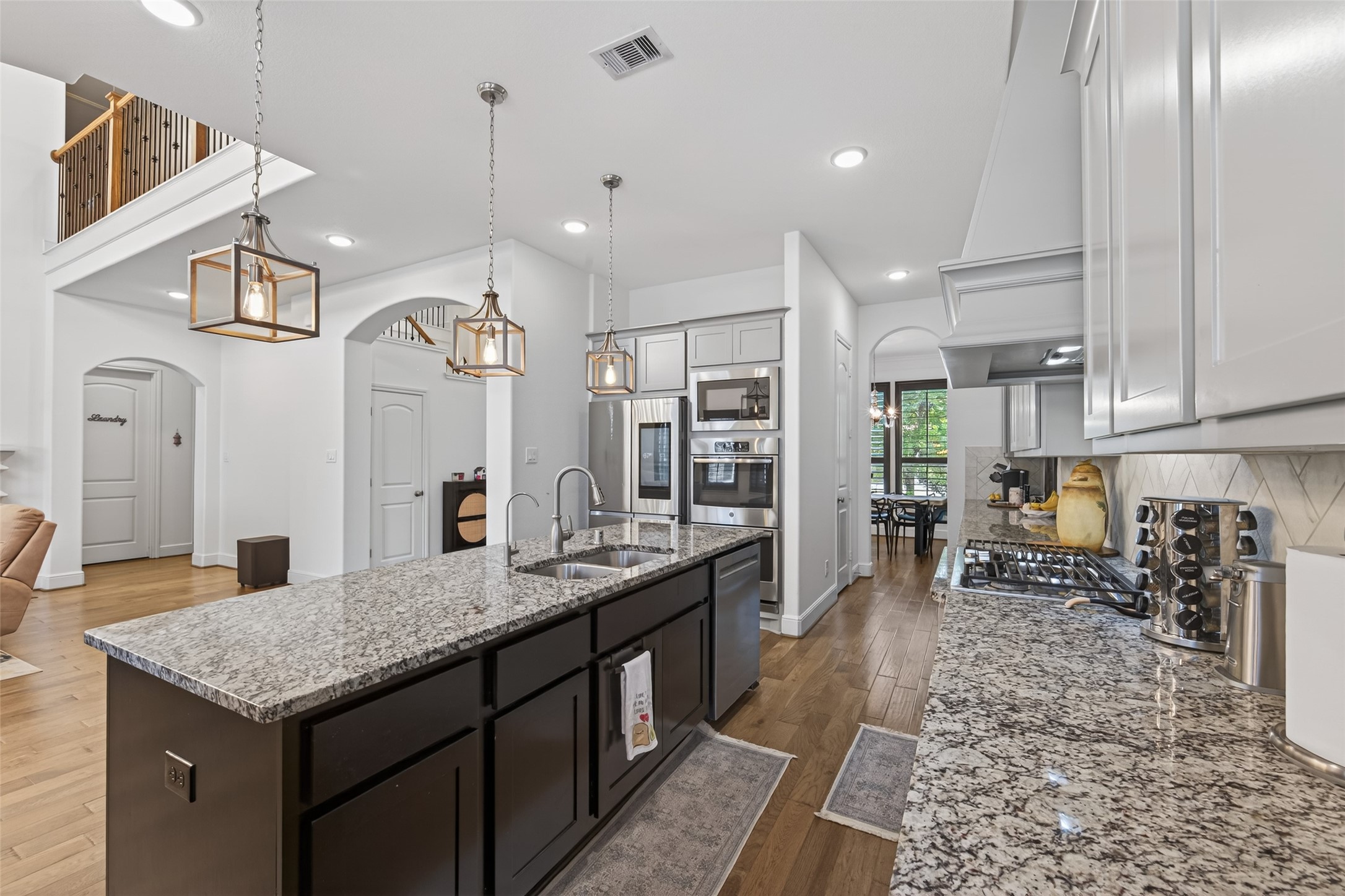 7014 Prairie Grass Lane Katy, TX 77493 - Photo 11 of 49 This kitchen features modern design with granite countertops, a large island, stainless steel appliances, and stylish pendant lighting. It has an open layout with hardwood floors and ample natural light, creating a bright and welcoming space.