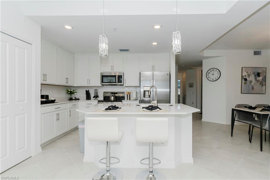 15285 Grn Acrs Avenue, Unit 418 Babcock Ranch, FL 33982 - Photo 4 of 49 a kitchen with white cabinets and chairs