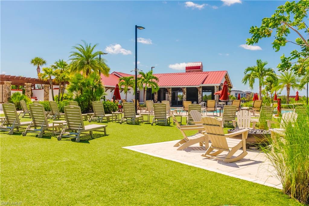 15285 Grn Acrs Avenue, Unit 418 Babcock Ranch, FL 33982 - Photo 42 of 49 a view of a swimming pool with a lawn chairs under an umbrella with palm trees
