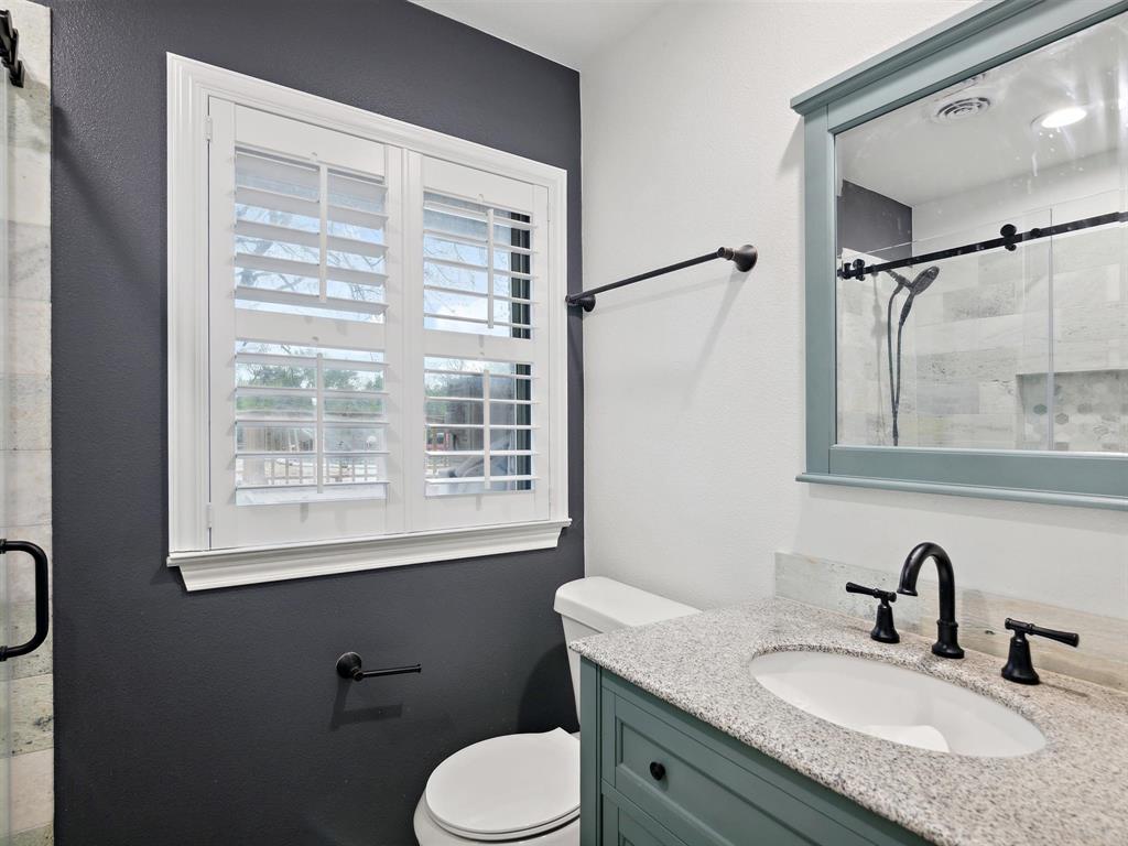 1302 Forreston Road Waxahachie, TX 75165 - Photo 35 of 39 a bathroom with a granite countertop sink toilet a mirror and shower