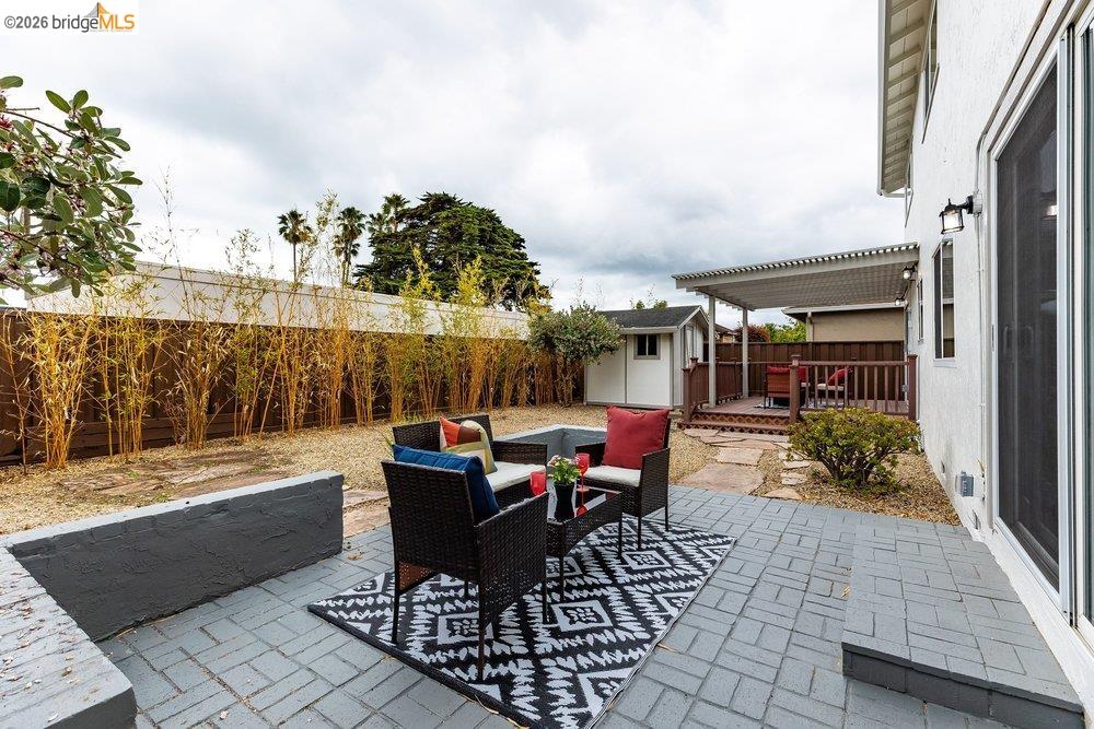 1298 Ribbon Street Foster City, CA 94404 - Photo 76 of 86 Expansive backyard featuring a gray paver patio, a raised wood deck with a slatted pergola, and a detached storage shed