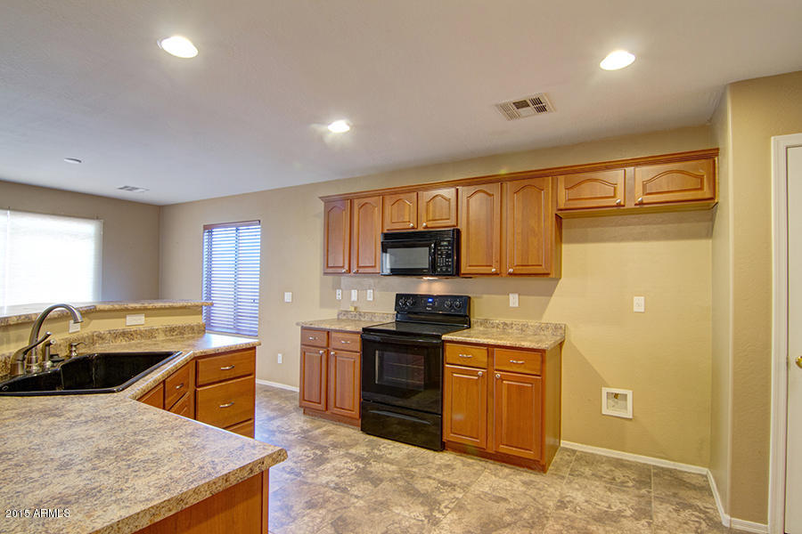 2404 West Roy Rogers Road Phoenix, AZ 85085 - Photo 5 of 35 a kitchen with stainless steel appliances granite countertop a sink stove refrigerator and cabinets