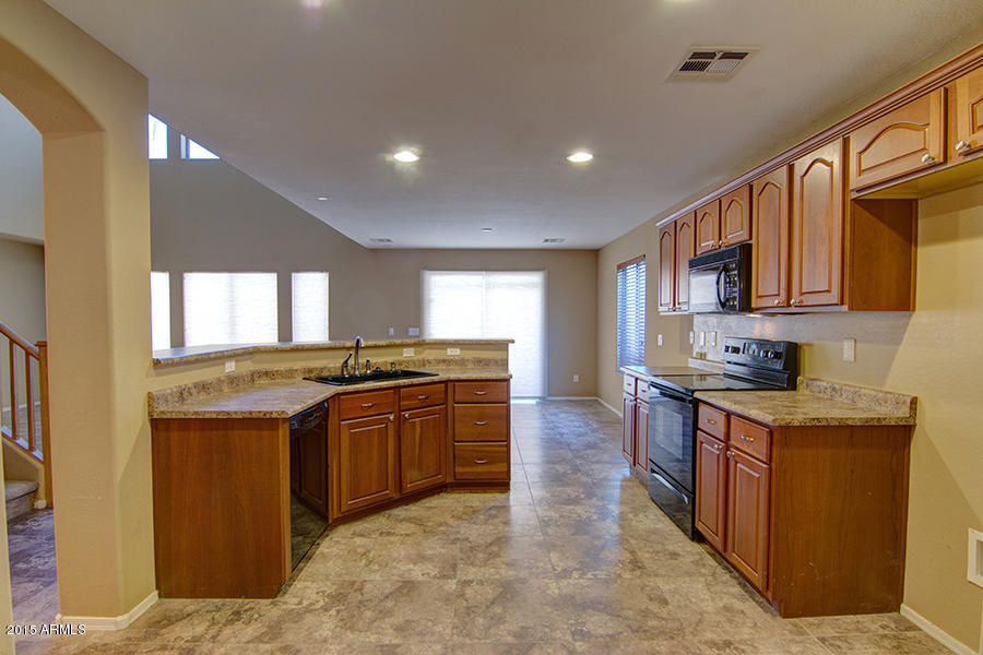 2404 West Roy Rogers Road Phoenix, AZ 85085 - Photo 6 of 35 a kitchen with stainless steel appliances granite countertop a stove top oven sink and cabinets