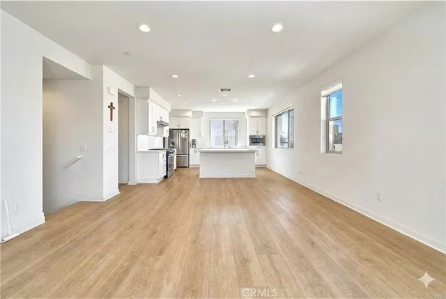 a view of a big room with wooden floor and windows
