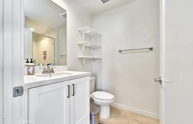 a bathroom with a granite countertop sink toilet and mirror