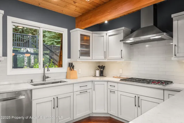 a kitchen with kitchen island granite countertop a stove top oven a sink a counter space and cabinets