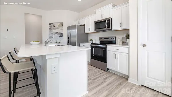 a kitchen with stainless steel appliances a stove a sink a microwave a refrigerator and cabinets