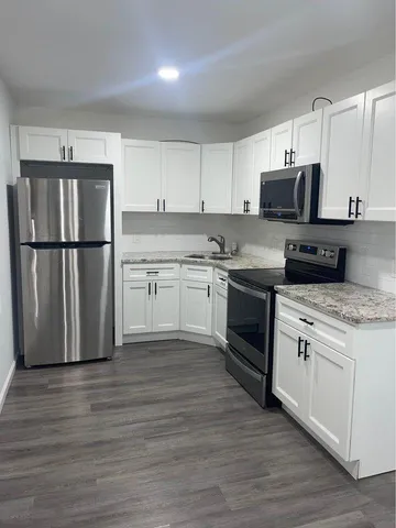 a kitchen with a sink a refrigerator a microwave and cabinets