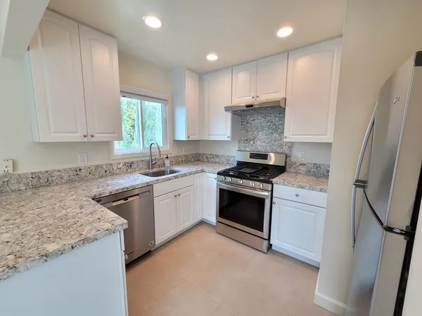 a kitchen with stainless steel appliances granite countertop a stove a sink and a refrigerator