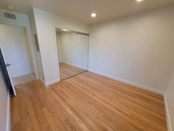 an empty room with wooden floor and entrance