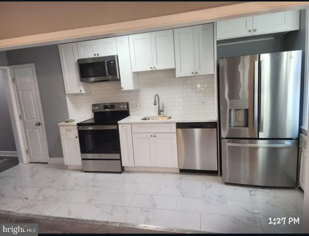 a kitchen with stainless steel appliances granite countertop a refrigerator stove a sink and a microwave