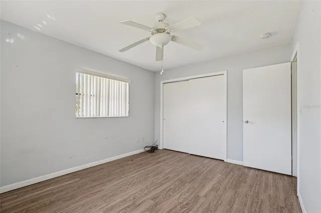 an empty room with wooden floor ceiling fan and windows