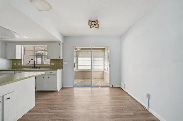 a kitchen with granite countertop a stove a sink and white cabinets with wooden floor
