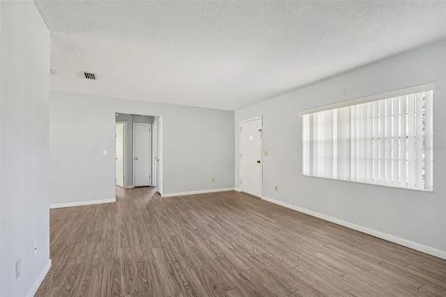 a view of an empty room with wooden floor and a window