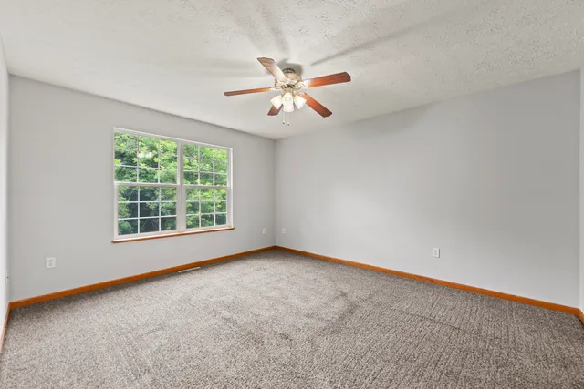 an empty room with a window and a fan