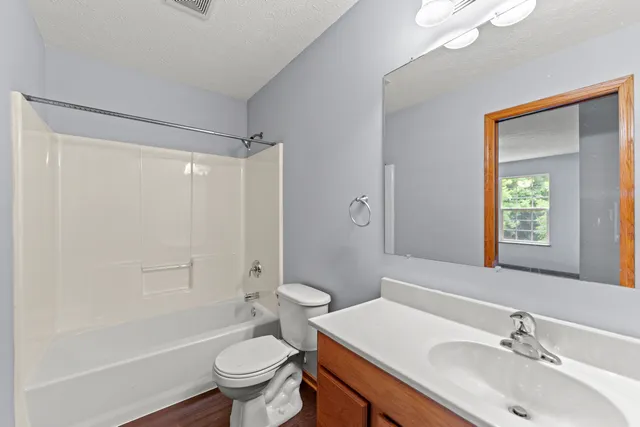 a bathroom with a sink toilet mirror vanity and shower