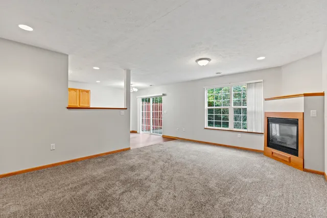 a view of an empty room with a window and fireplace
