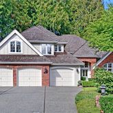 a front view of a house with garage and trees