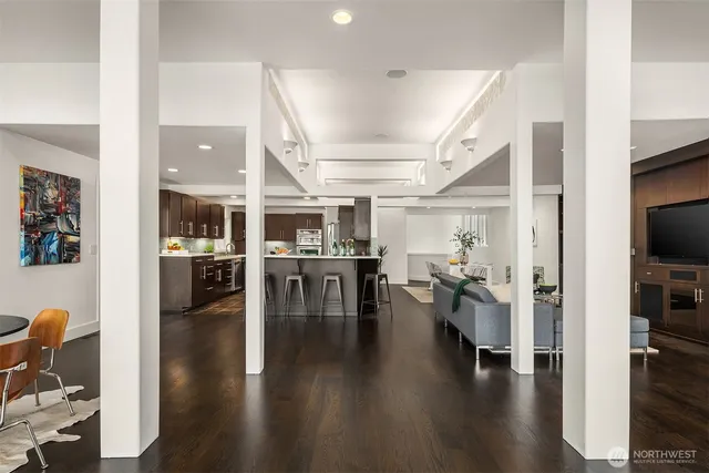 a living room with furniture a rug and white kitchen