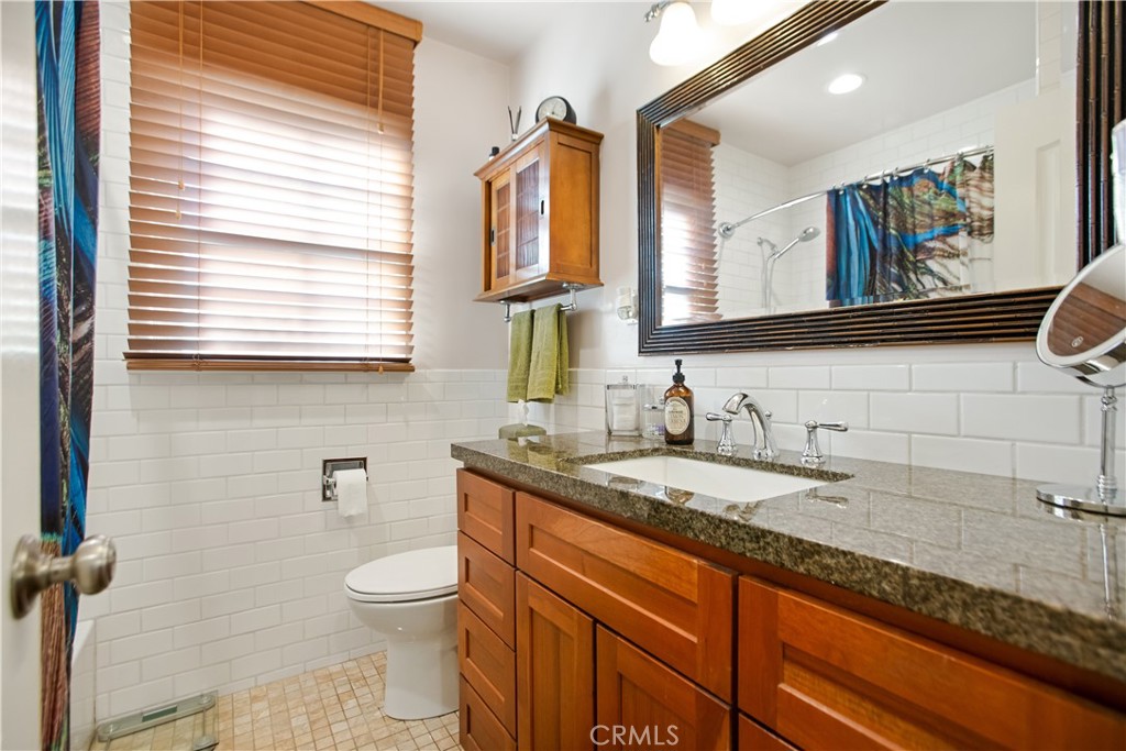 9253 Rose Street Bellflower, CA 90706 - Photo 22 of 36 a bathroom with a granite countertop toilet sink and mirror