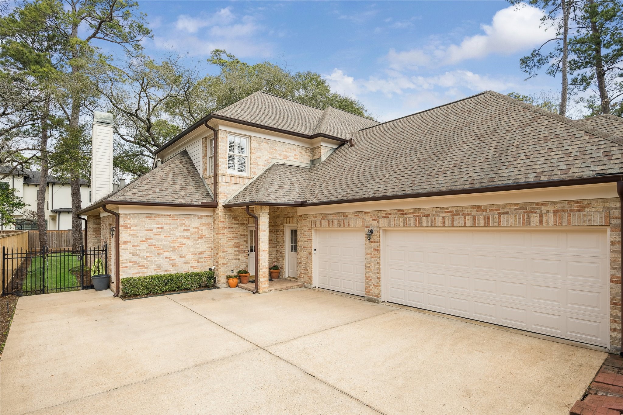 11524 Taylorcrest Road Houston, TX 77024 - Photo 44 of 47 A spacious motor court with a wrought iron motorized driveway gate leads to a side entry and a three-car garage, offering ample parking and easy access.