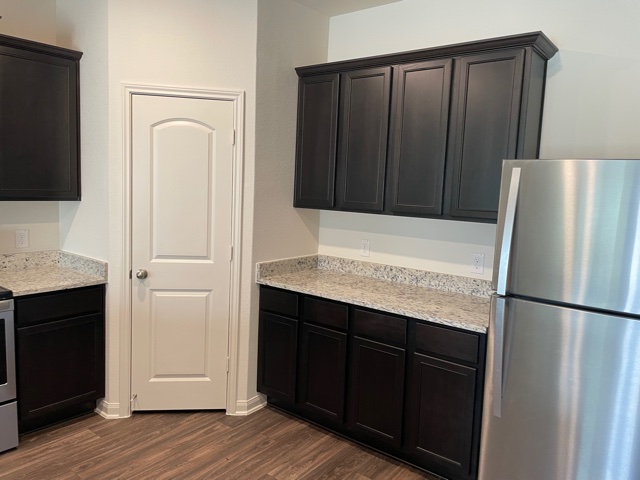 18741 Speculator Lane Elgin, TX 78621 - Photo 11 of 28 a kitchen with stainless steel appliances granite countertop a refrigerator and a sink with wooden cabinets