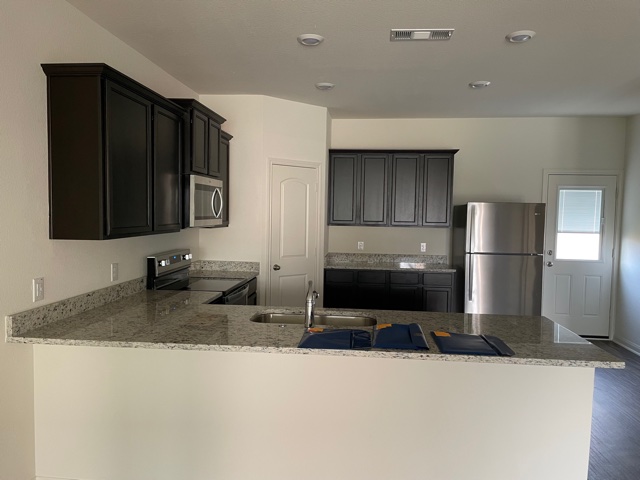 18741 Speculator Lane Elgin, TX 78621 - Photo 7 of 28 a kitchen with stainless steel appliances granite countertop a sink refrigerator and microwave