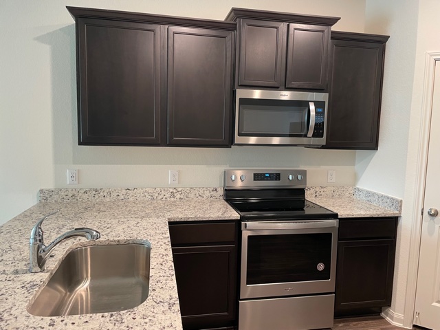 18741 Speculator Lane Elgin, TX 78621 - Photo 8 of 28 a kitchen with granite countertop a sink and a microwave