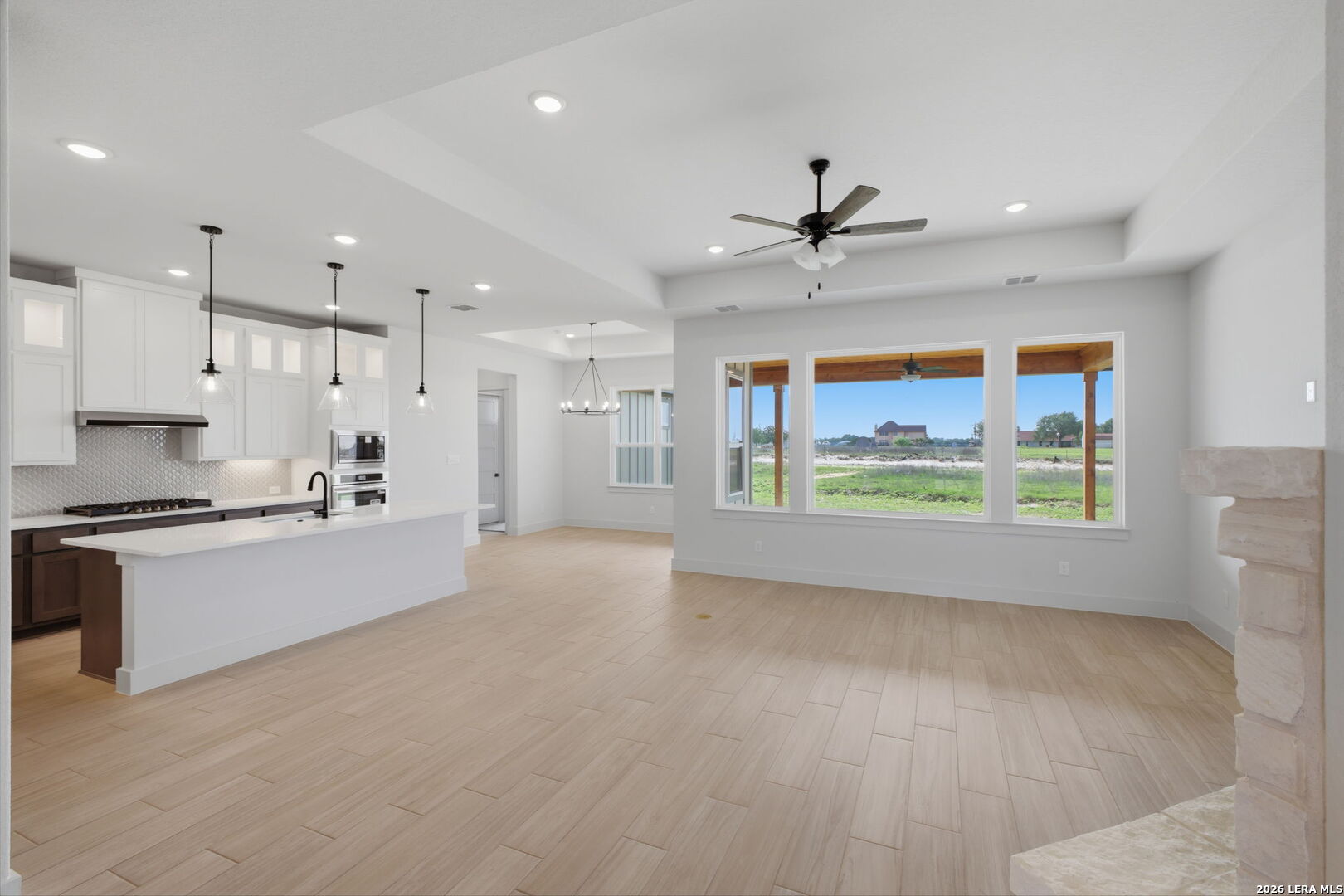 171 Pradera Ridge Drive Floresville, TX 78114 - Photo 2 of 18 a large kitchen with stainless steel appliances a large counter top a stove a sink dishwasher and a refrigerator with wooden floor