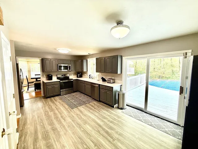 a large kitchen with a sink stainless steel appliances and white cabinets