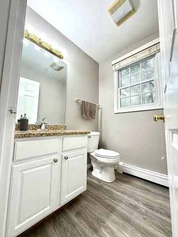 a bathroom with a granite countertop toilet sink and mirror